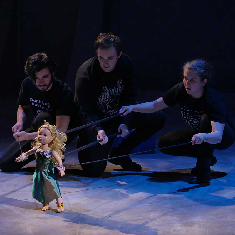 Three Puppeteers Move Small Doll
